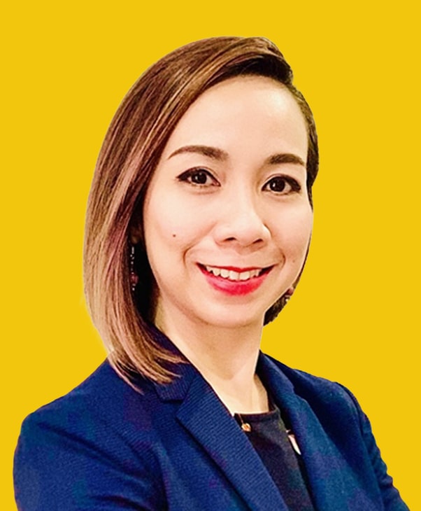 Smiling woman in navy blazer on yellow background, professional and positive.