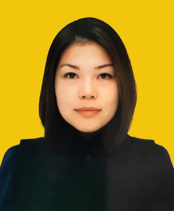 Person with shoulder-length dark hair in dark top on yellow background, calm expression.