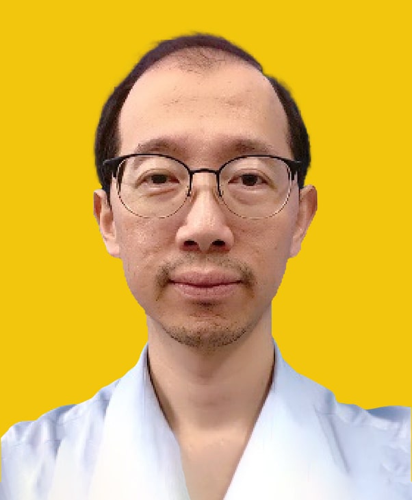 Man in glasses and light blue shirt on yellow background, calm and focused.