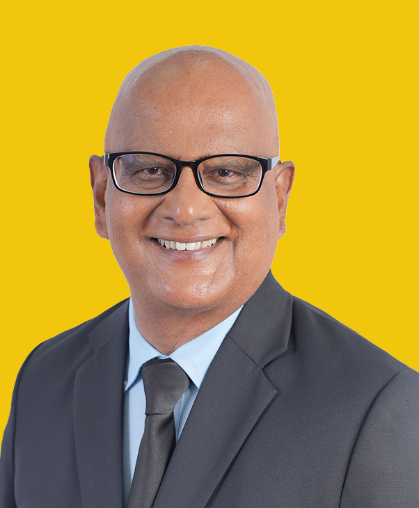 Smiling bald man in glasses, suit, and tie on yellow background.