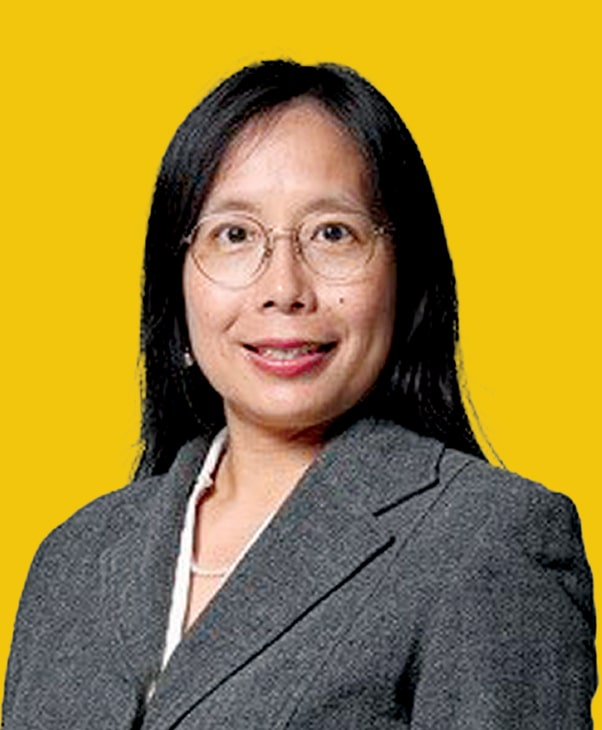 Person with long black hair and glasses in grey blazer on yellow background.