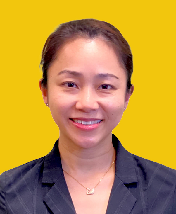 Smiling woman in dark suit with necklace on yellow background, professional and cheerful.